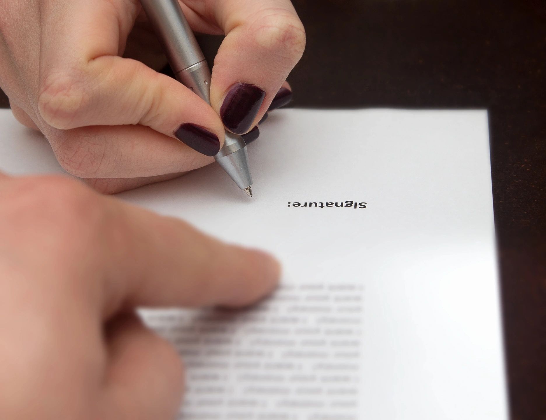 Hand signing document with pen
